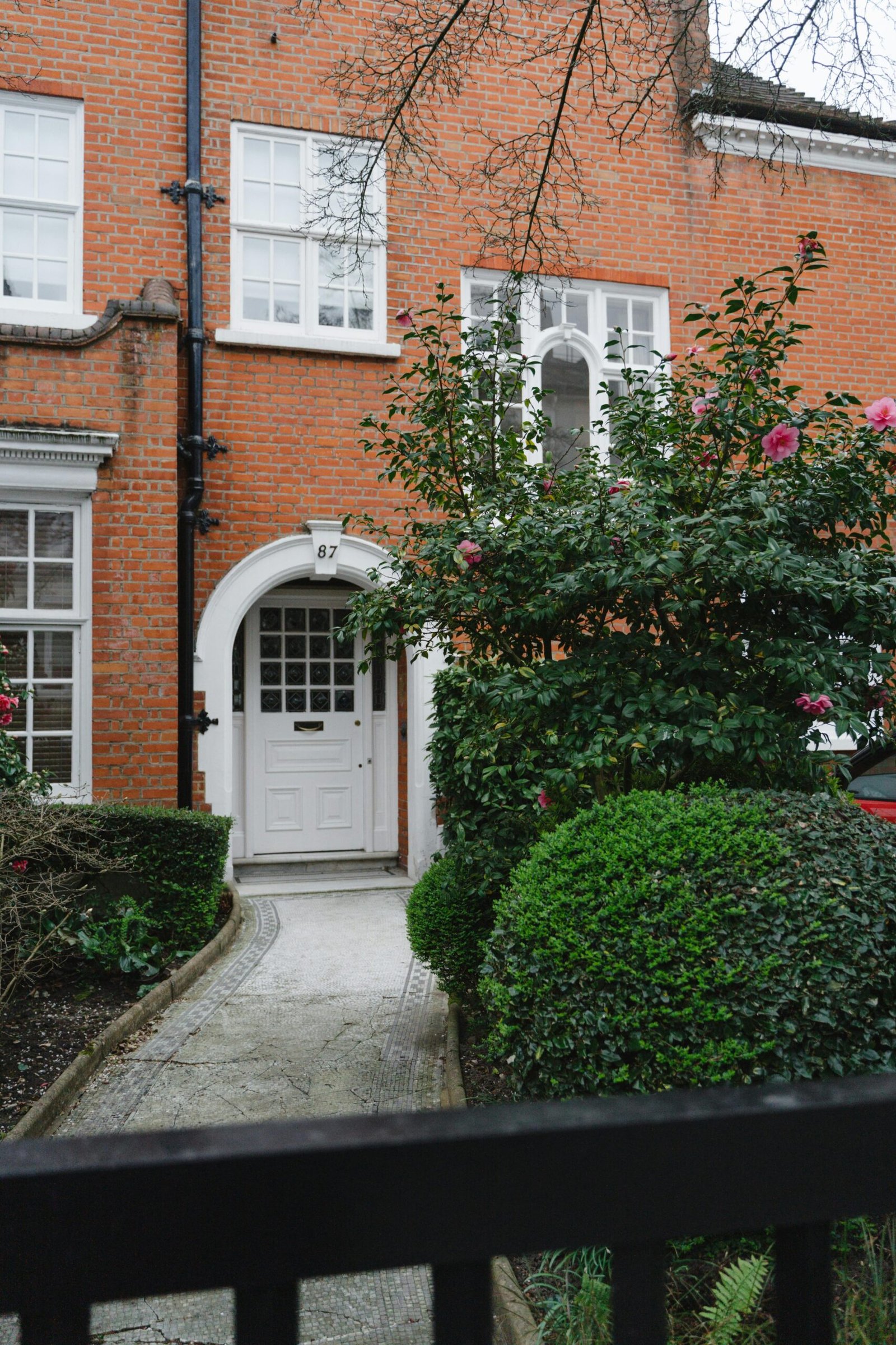 A picturesque red brick facade with vibrant greenery in London, England.